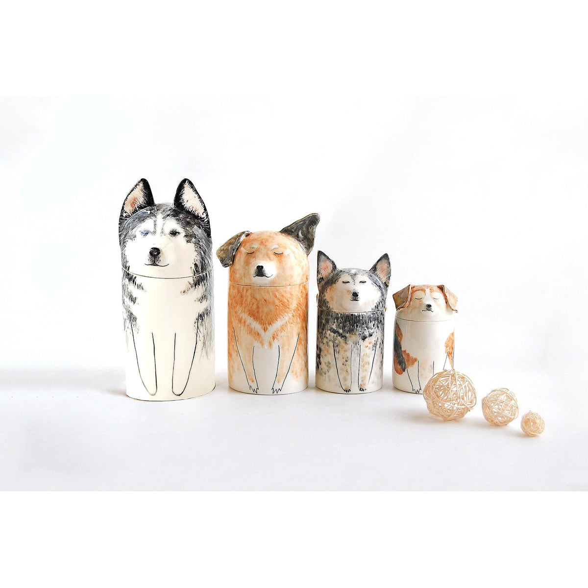 Four personalized ceramic dog urns displayed together in different sizes and painted markings