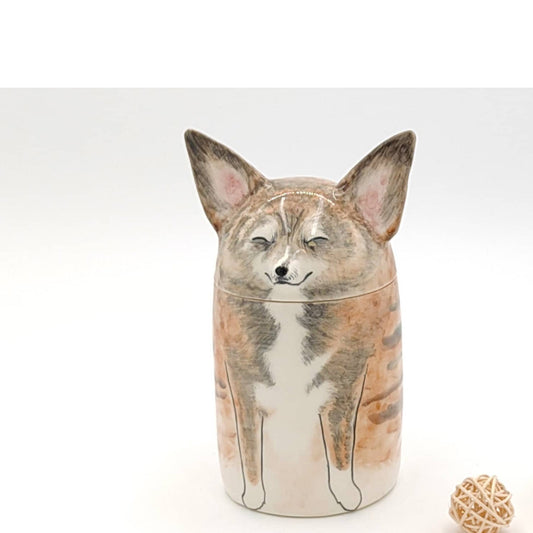 Handmade ceramic dog urn with closed eyes, painted fur markings and a rounded head lid